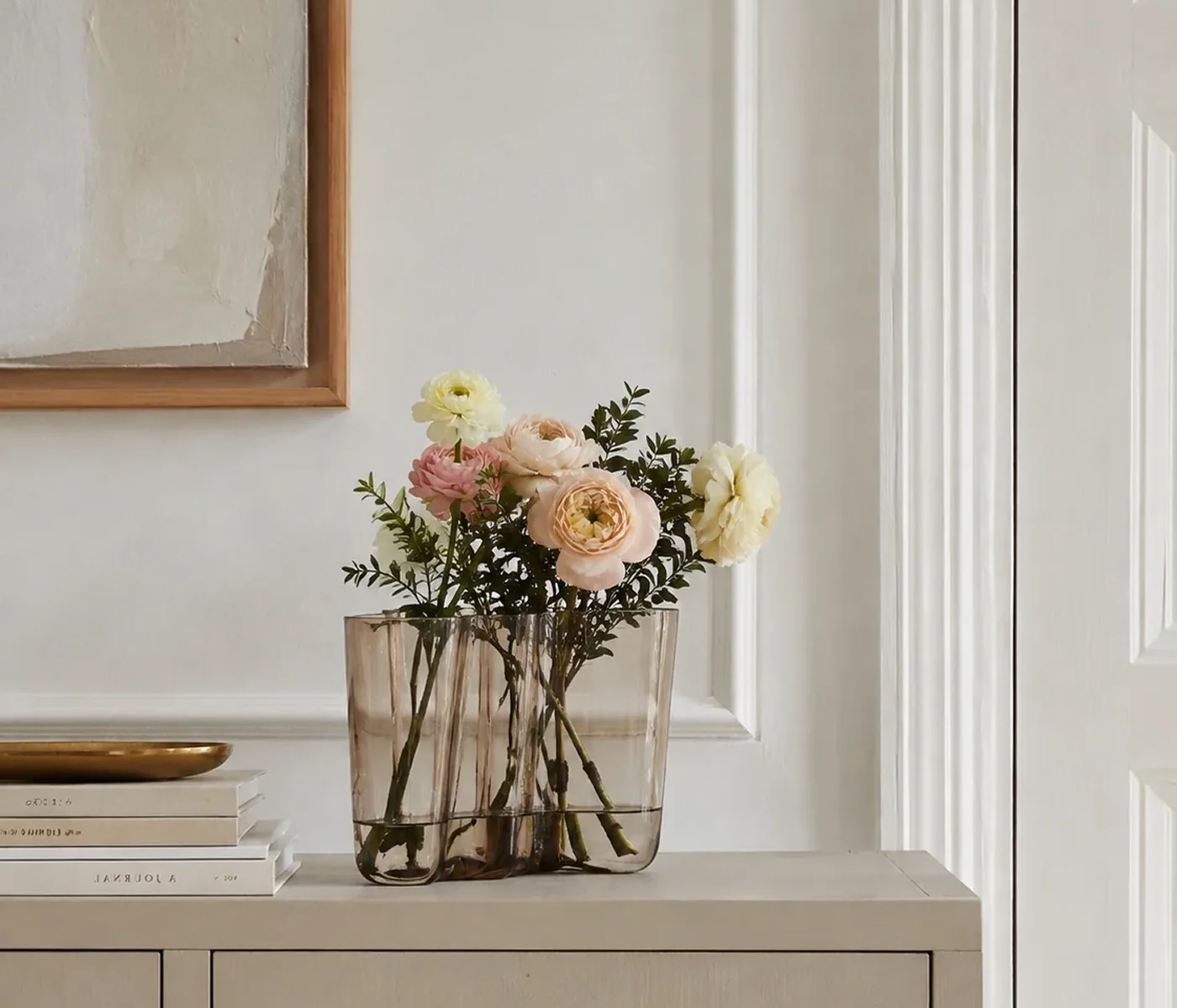 Alvar Aalto Vase mit hellem Blumenstrauß neben gerahmtem Bild