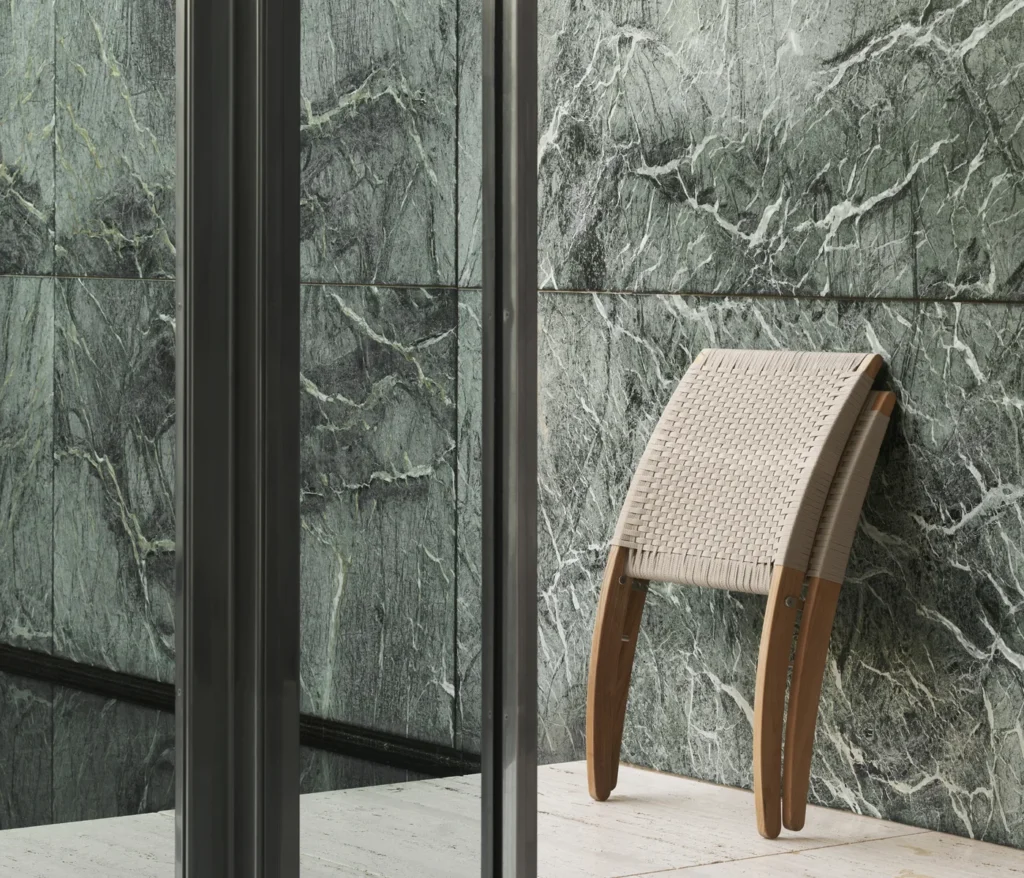 Zusammengeklappter Carl Hansen MG501 Cuba Chair aus Teak vor einer grünen Marmorwand