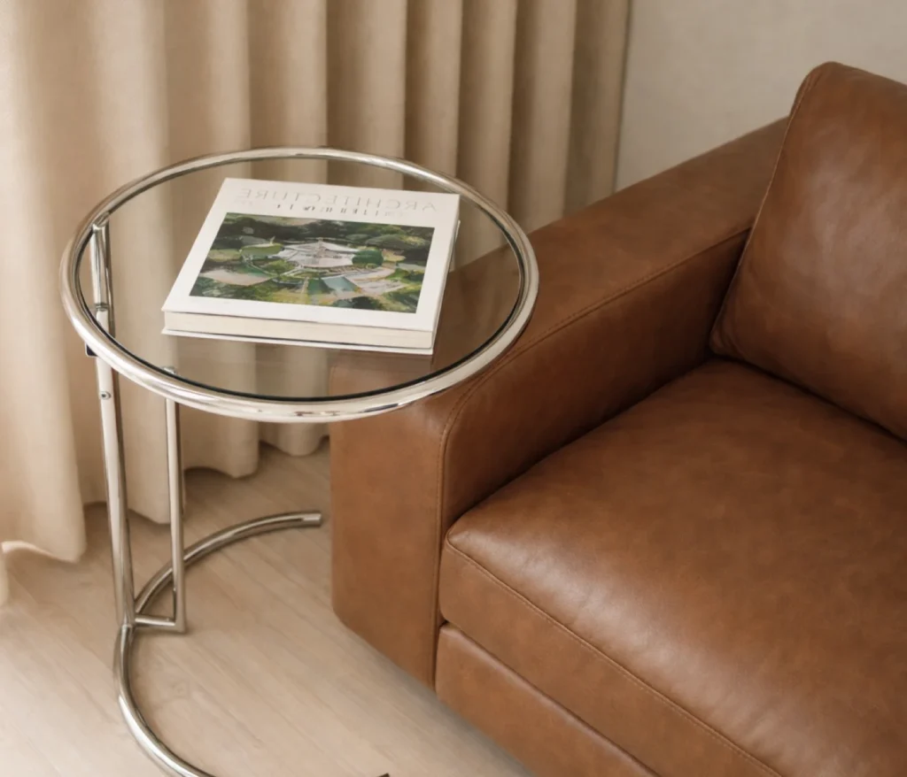 ClassiCon Adjustable Table E 1027 von Eileen Gray neben einem Ledersofa