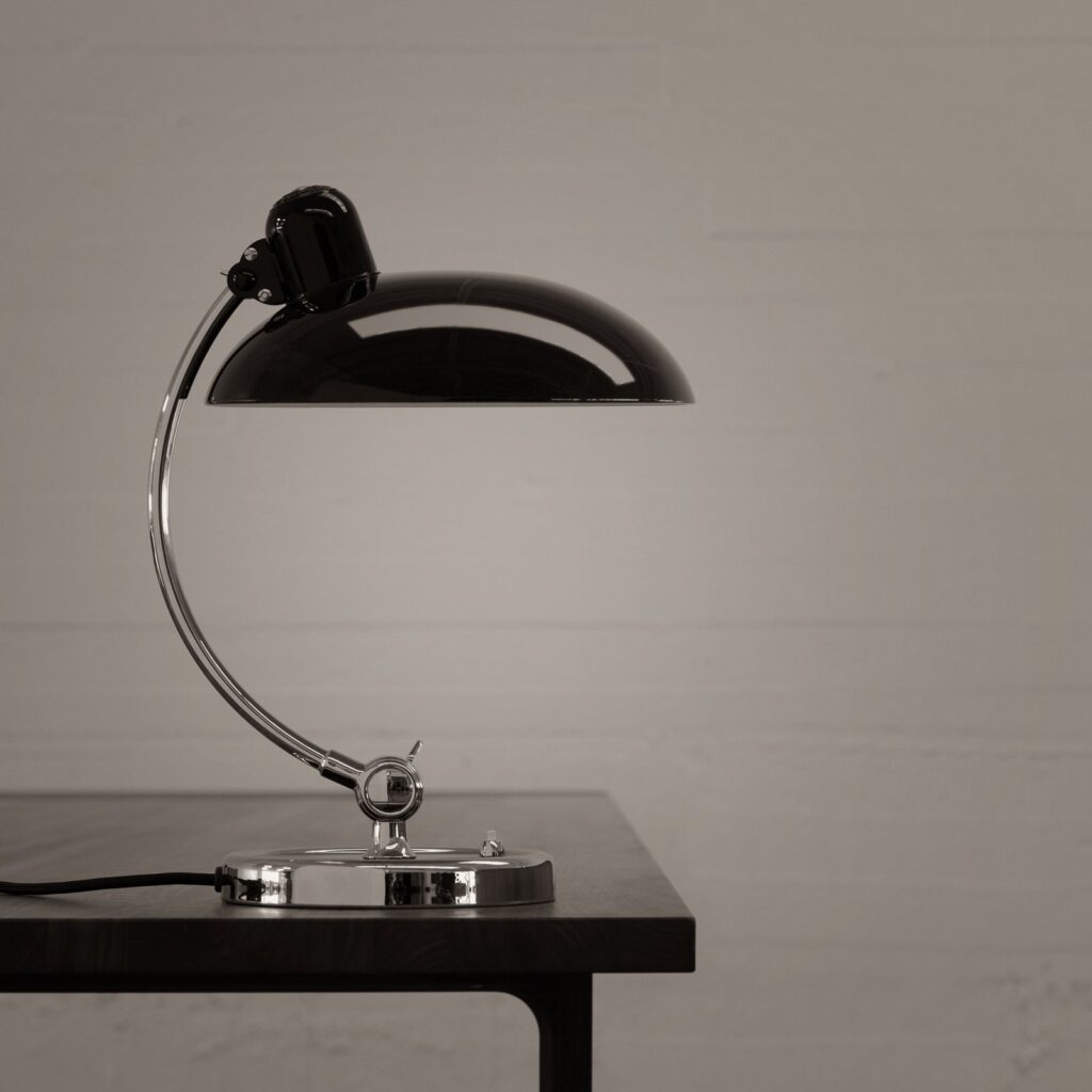 Kaiser Idell 6631-T Luxus in Schwarz mit verchromtem Arm auf einem dunklen Tisch