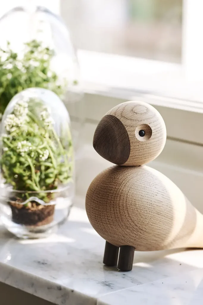 Kay Bojesen Singvogel Alfred aus Eiche auf einer Marmorplatte neben Pflanzen