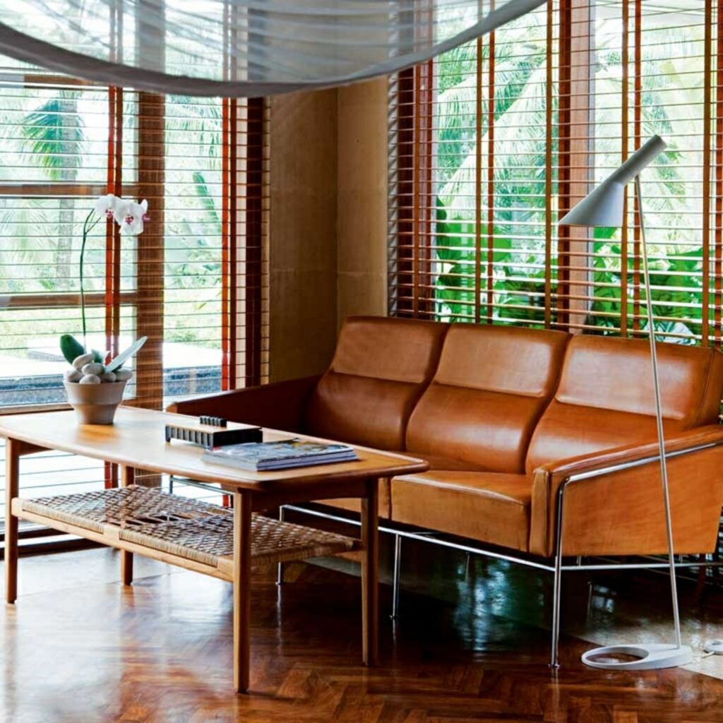 Louis Poulsen AJ Stehleuchte in Weiß neben einem Ledersofa und einem Couchtisch aus Holz vor Holzjalousien