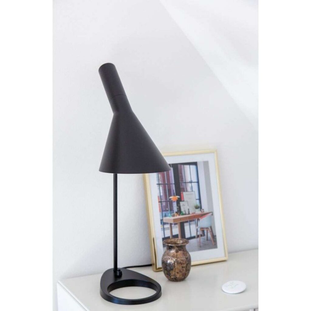 Louis Poulsen AJ Tischleuchte in Schwarz auf einem weißen Sideboard neben einem gerahmten Bild