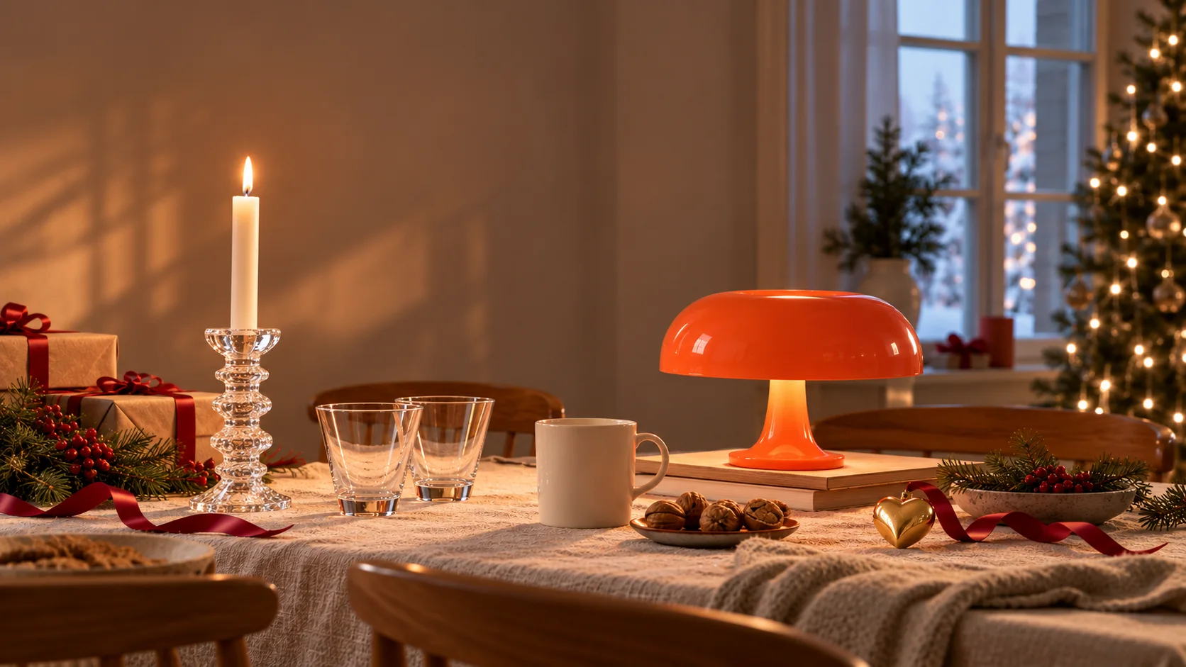 Weihnachtlich gedeckter Tisch mit Iittala Festivo Kerzenhalter, Kartio Gläsern, Teema Tasse, Artemide Nessino in Orange und Georg Jensen Herz, im Hintergrund ein Weihnachtsbaum