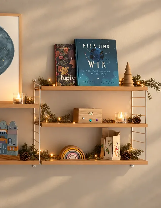 String Pocket Regal mit weißen Leitern, Büchern und Lichterkette an einer hellen Wand
